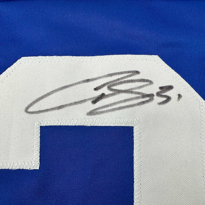 Close-up of handwritten signature in black ink on white fabric patch of blue hockey jersey.
