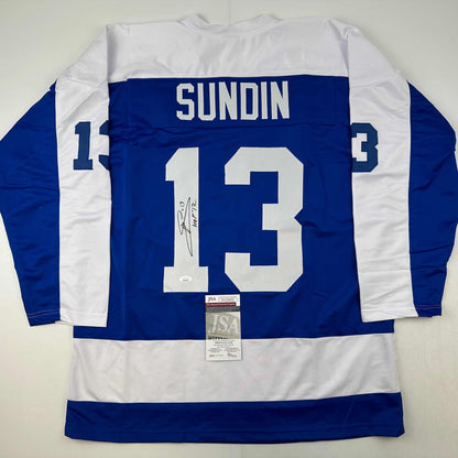 Back view of blue and white striped hockey jersey number 13 with "SUNDIN" nameplate and autographed signature, JSA authentication certificate visible.