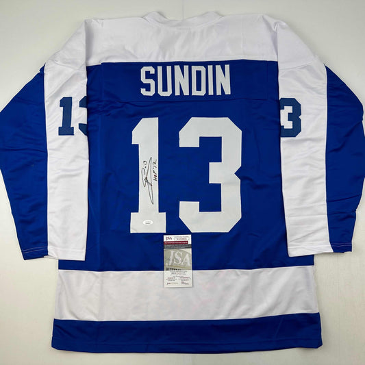 Back view of blue and white striped hockey jersey number 13 with "SUNDIN" nameplate and autographed signature, JSA authentication certificate visible.