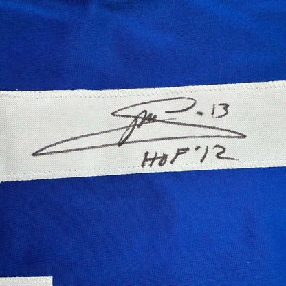Close-up of handwritten signature and "HOF '12" on white stripe of blue hockey jersey.