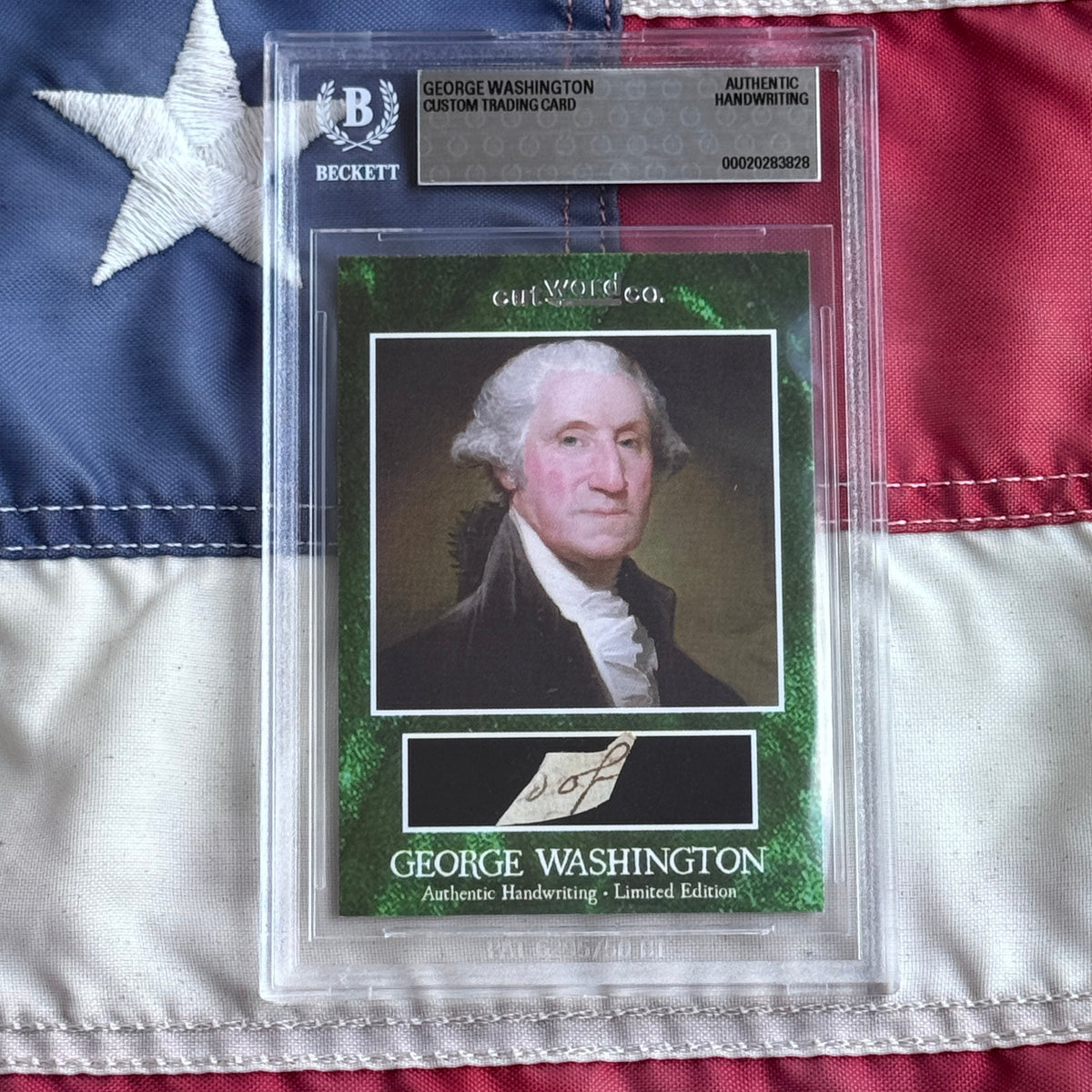 Front view of a sealed Beckett slab on a flag, showing a green card with a portrait and handwriting.
