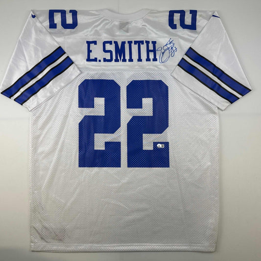White Dallas Cowboys jersey number 32 with E. Smith nameplate and blue autographed signature, displayed flat lay front view.