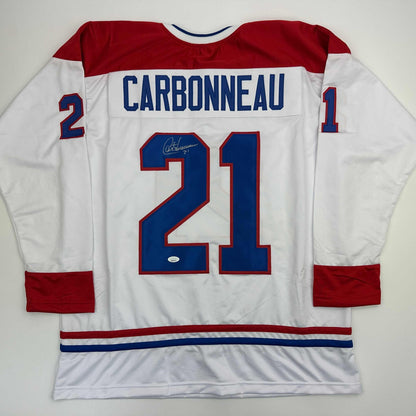 Autographed Montreal Canadiens jersey number 21 displaying Carbonneau nameplate, white body with red and blue trim, flat lay back view.