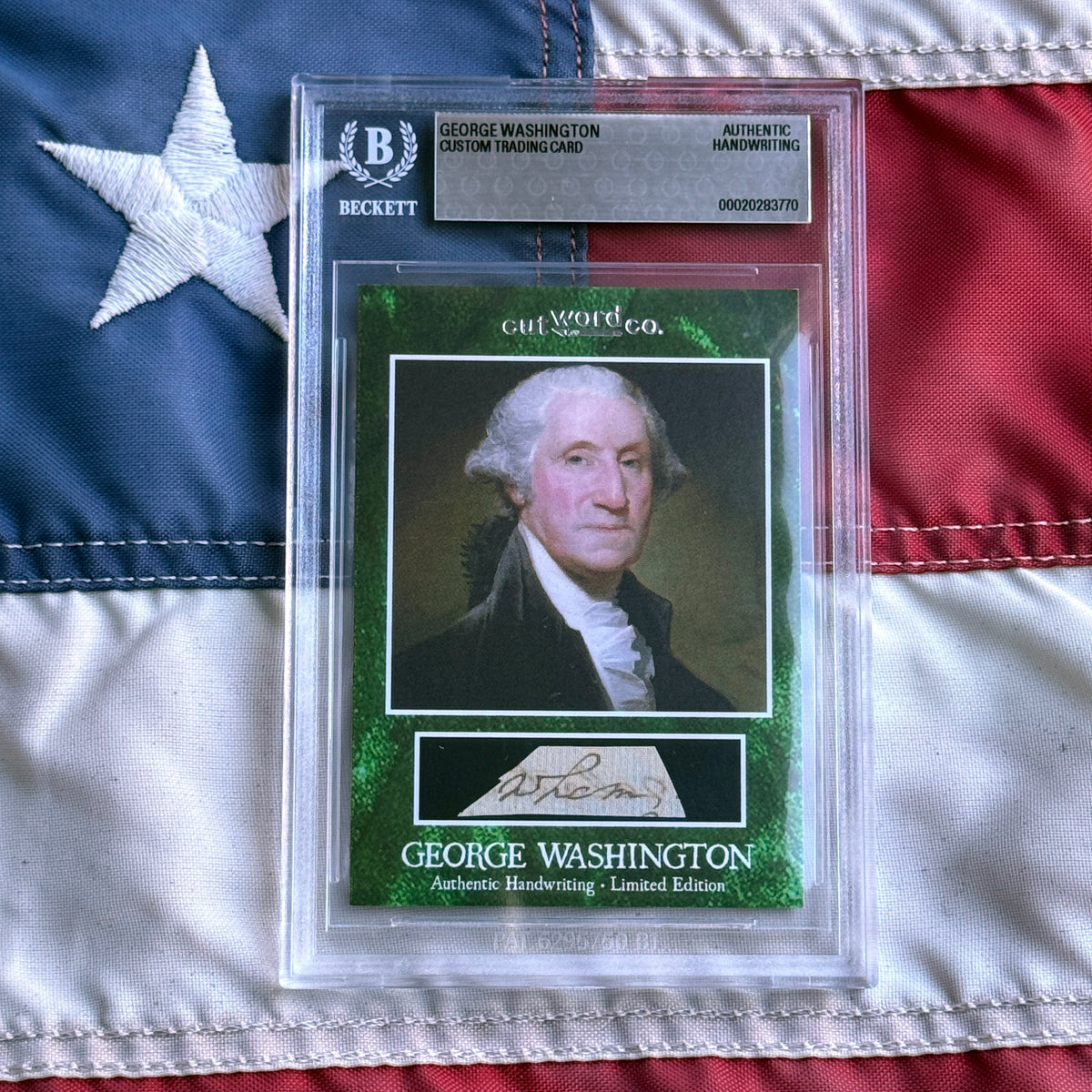 Front view of a Beckett-graded slab on a flag, showing a green card with a painted portrait and handwriting cutout.