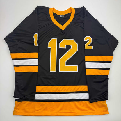Black and gold hockey jersey number 12 with orange and white stripes, displayed flat against white background.