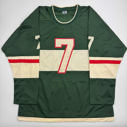 Front view of green, cream, and red striped hockey jersey with number 7 in red and cream outlined lettering.