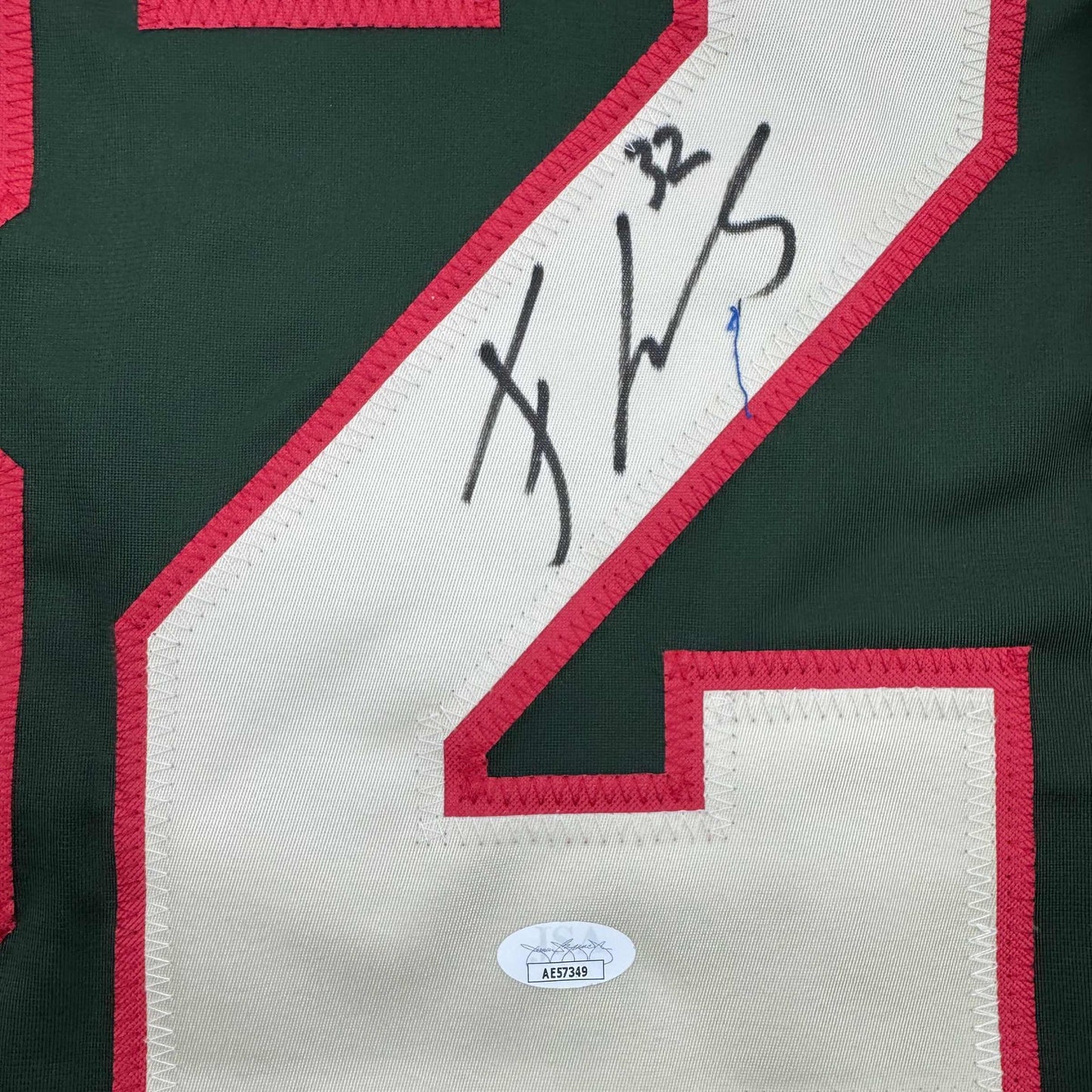 Close-up of signed green and red hockey jersey nameplate with handwritten signature and JSA authentication sticker visible.