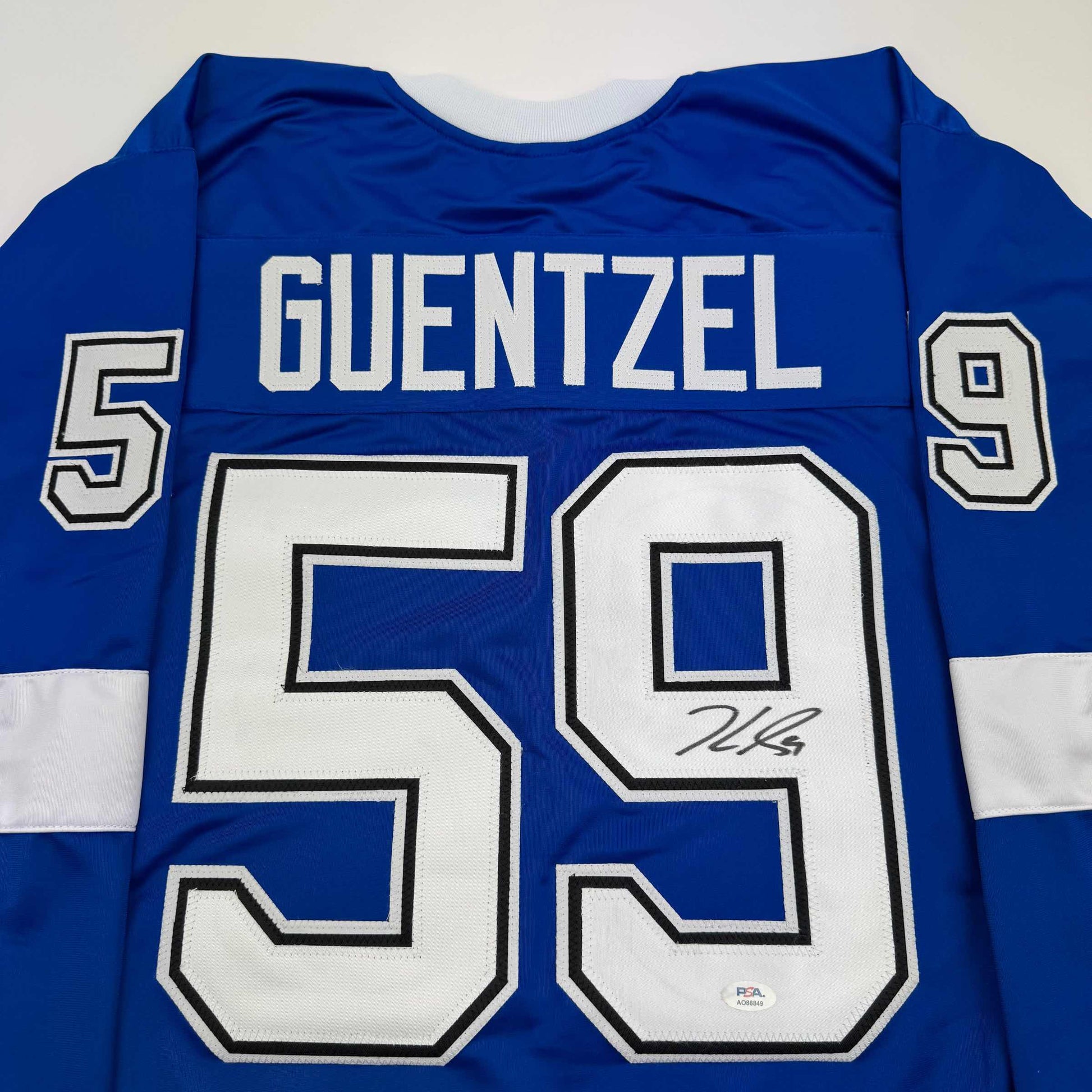 Back view of blue hockey jersey with white "GUENTZEL" name and "59" number, displaying autograph on number.