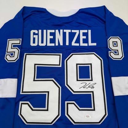Back view of blue hockey jersey with white "GUENTZEL" name and "59" number, displaying autograph on number.
