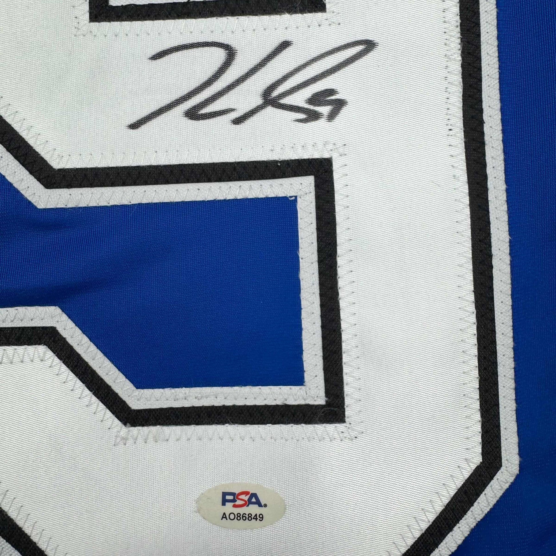 Close-up of autographed Jake Guentzel jersey showing handwritten signature on white panel with blue and black geometric design and PSA authentication sticker.