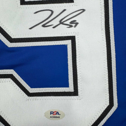 Close-up of autographed Jake Guentzel jersey showing handwritten signature on white panel with blue and black geometric design and PSA authentication sticker.