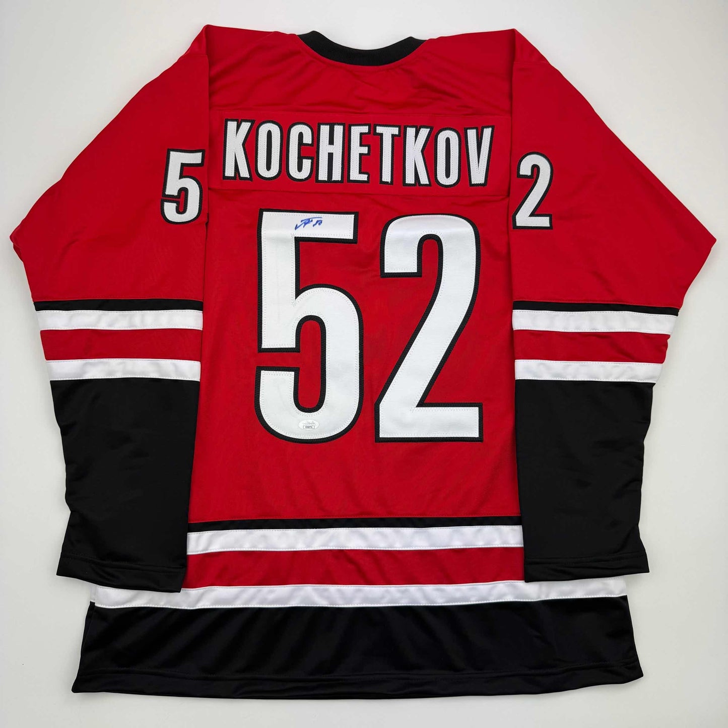 Red Carolina hockey jersey with black and white stripes displaying "KOCHETKOV" and number 52, shown flat lay from back view.