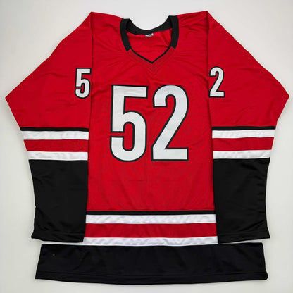 Red hockey jersey with number 52 displayed flat against white background, showing front view with black and white striping on sleeves and torso.