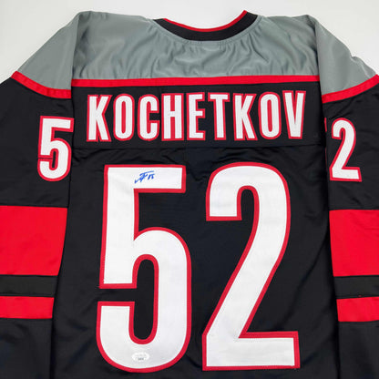 Back view of black and red striped hockey jersey with "KOCHETKOV" and number 52 printed across shoulders, large number 59 on back, and autograph visible on white number.