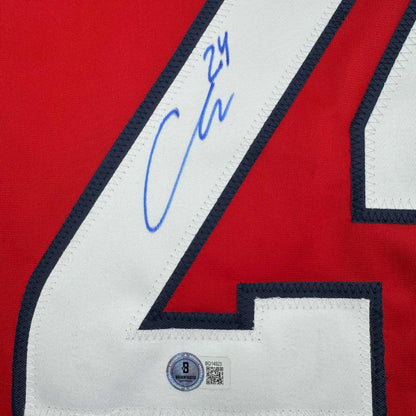 Close-up of signed red hockey jersey white stripe with blue autograph and Beckett authentication hologram visible.
