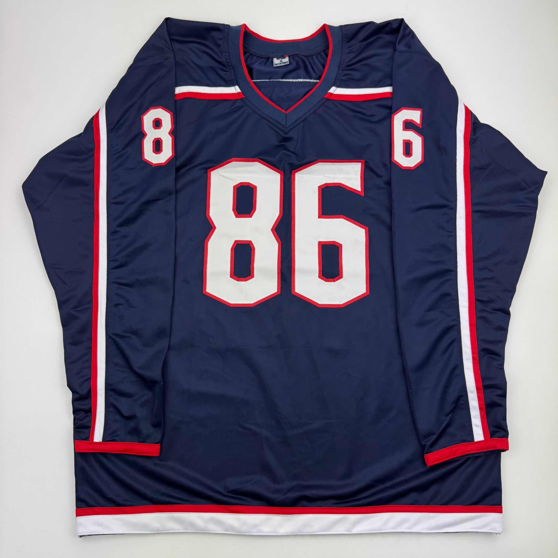 Navy blue hockey jersey with white and red trim displaying number 86 on front, laid flat against white background.