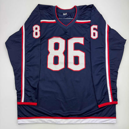 Navy blue hockey jersey with white and red trim displaying number 86 on front, laid flat against white background.