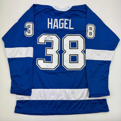 Blue and white striped hockey jersey displaying "HAGEL" and number 38 on back, laid flat on white background.