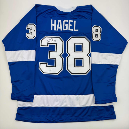 Blue and white striped hockey jersey displaying "HAGEL" and number 38 on back, laid flat on white background.