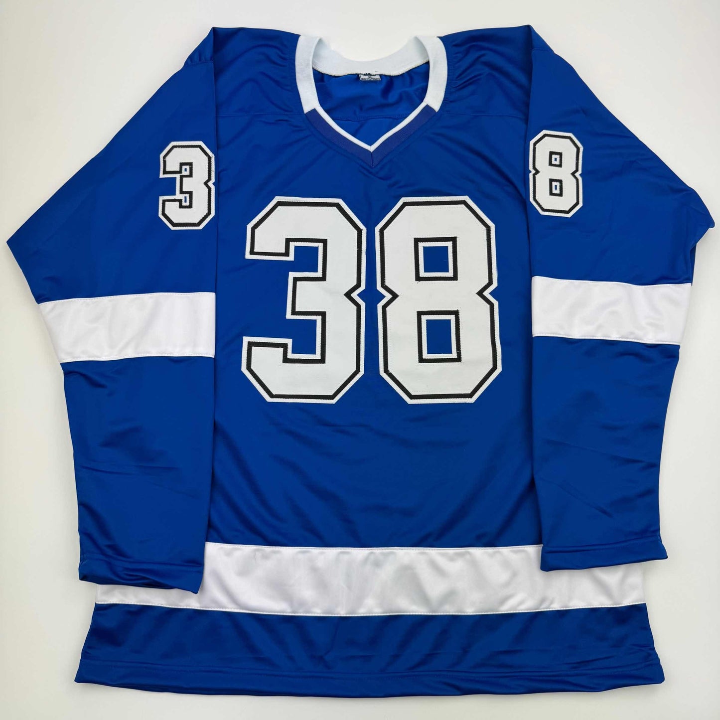 Blue and white striped hockey jersey displayed flat, showing number 38 on chest and numbers 3 and 8 on sleeves.