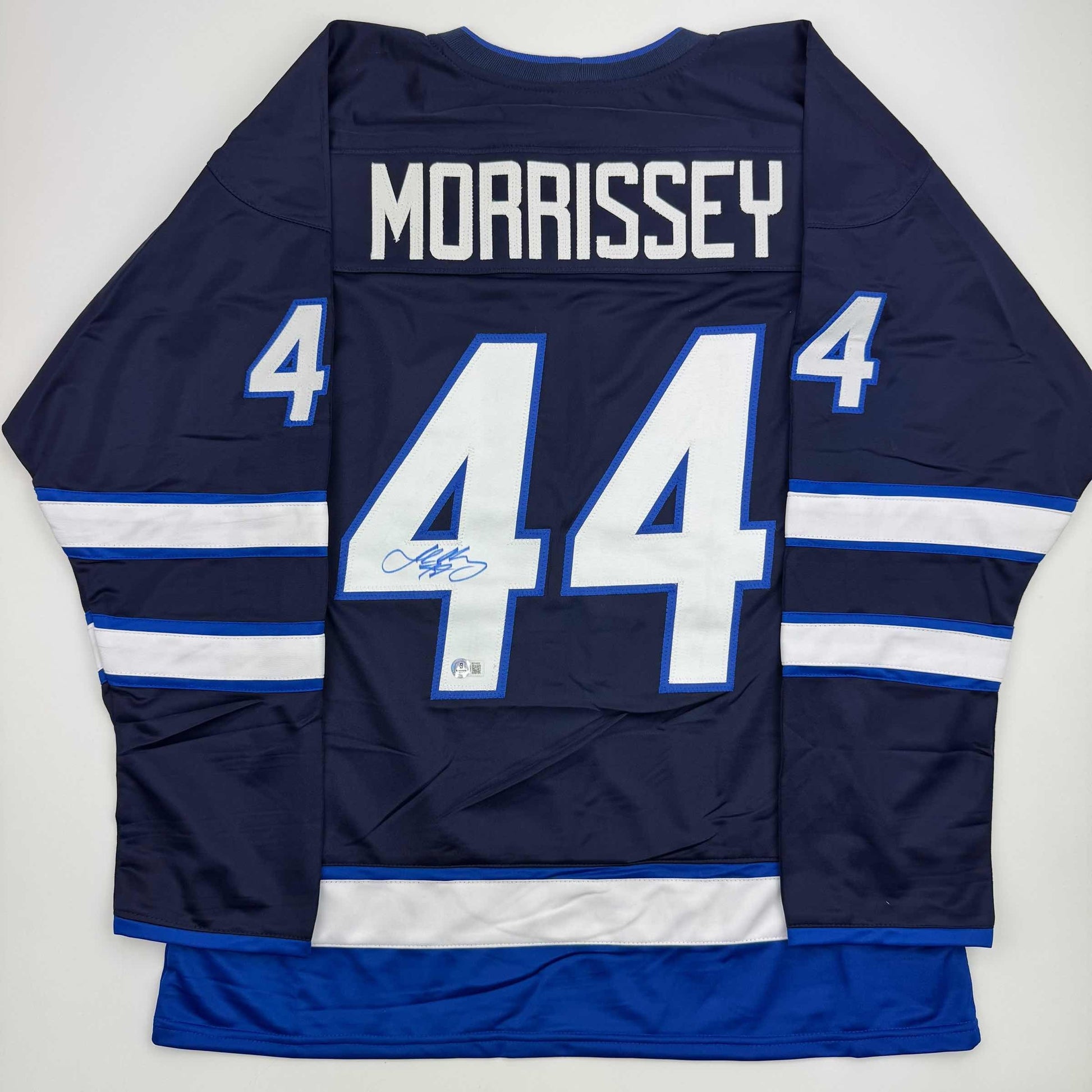 Back view of navy blue Winnipeg Jets hockey jersey number 44 with "MORRISSEY" nameplate and autographed number, white and blue striping visible.