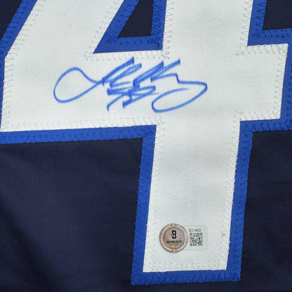 Close-up of blue autographed hockey jersey showing signed nameplate with Beckett authentication sticker and QR code.