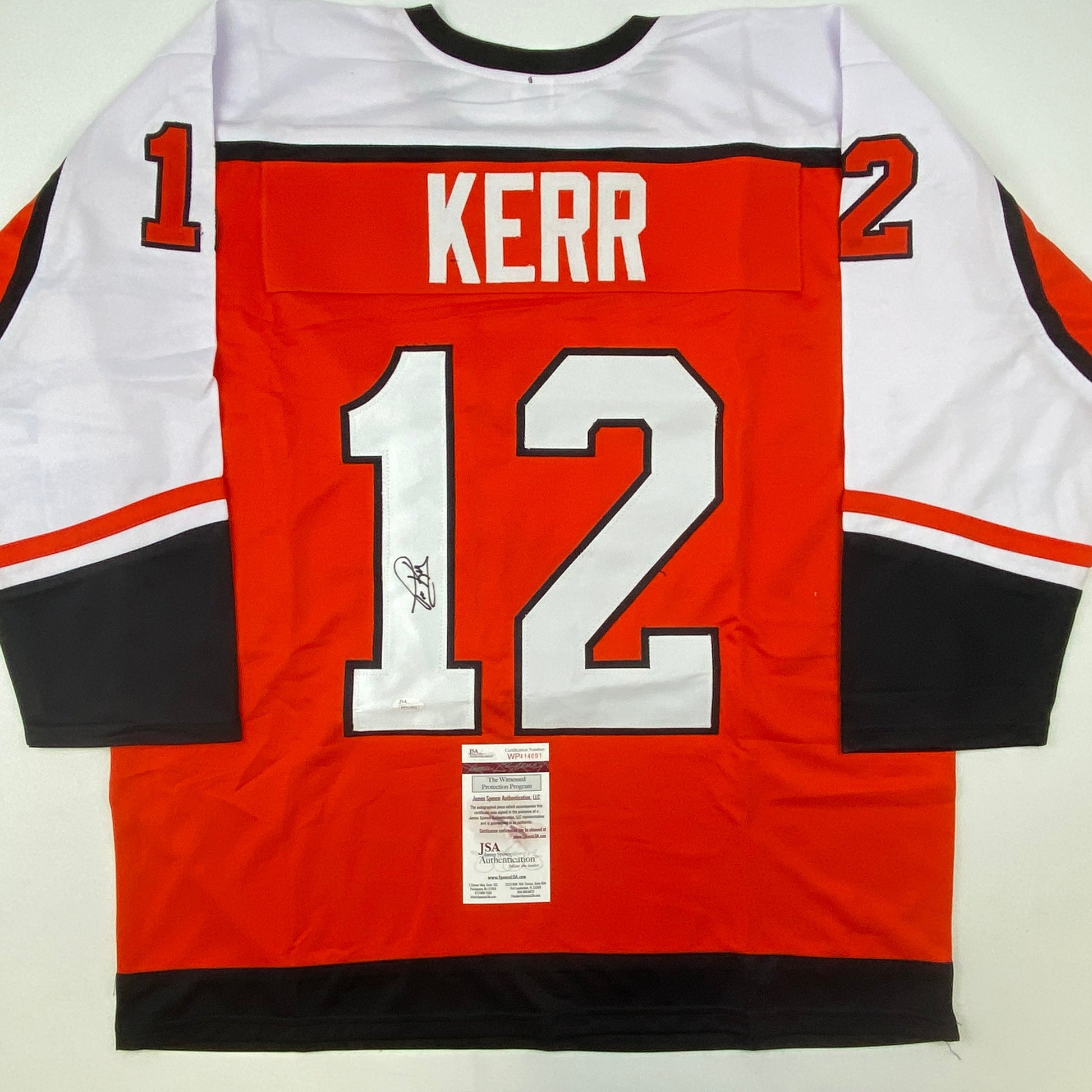 Signed red Philadelphia hockey jersey number 12 with "KERR" nameplate, displayed flat showing back with JSA authentication certificate.