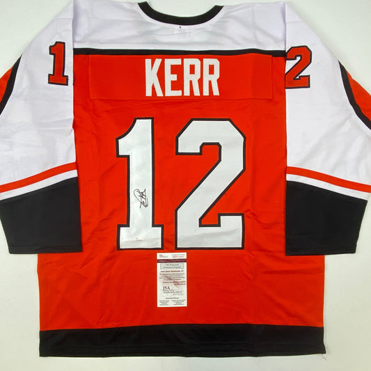 Signed red Philadelphia hockey jersey number 12 with "KERR" nameplate, displayed flat showing back with JSA authentication certificate.