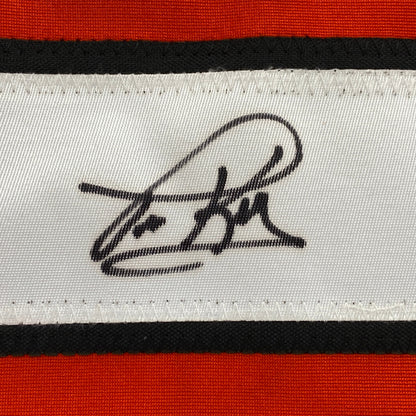 Close-up of black handwritten signature on white stripe of red, black, and white horizontal striped fabric.