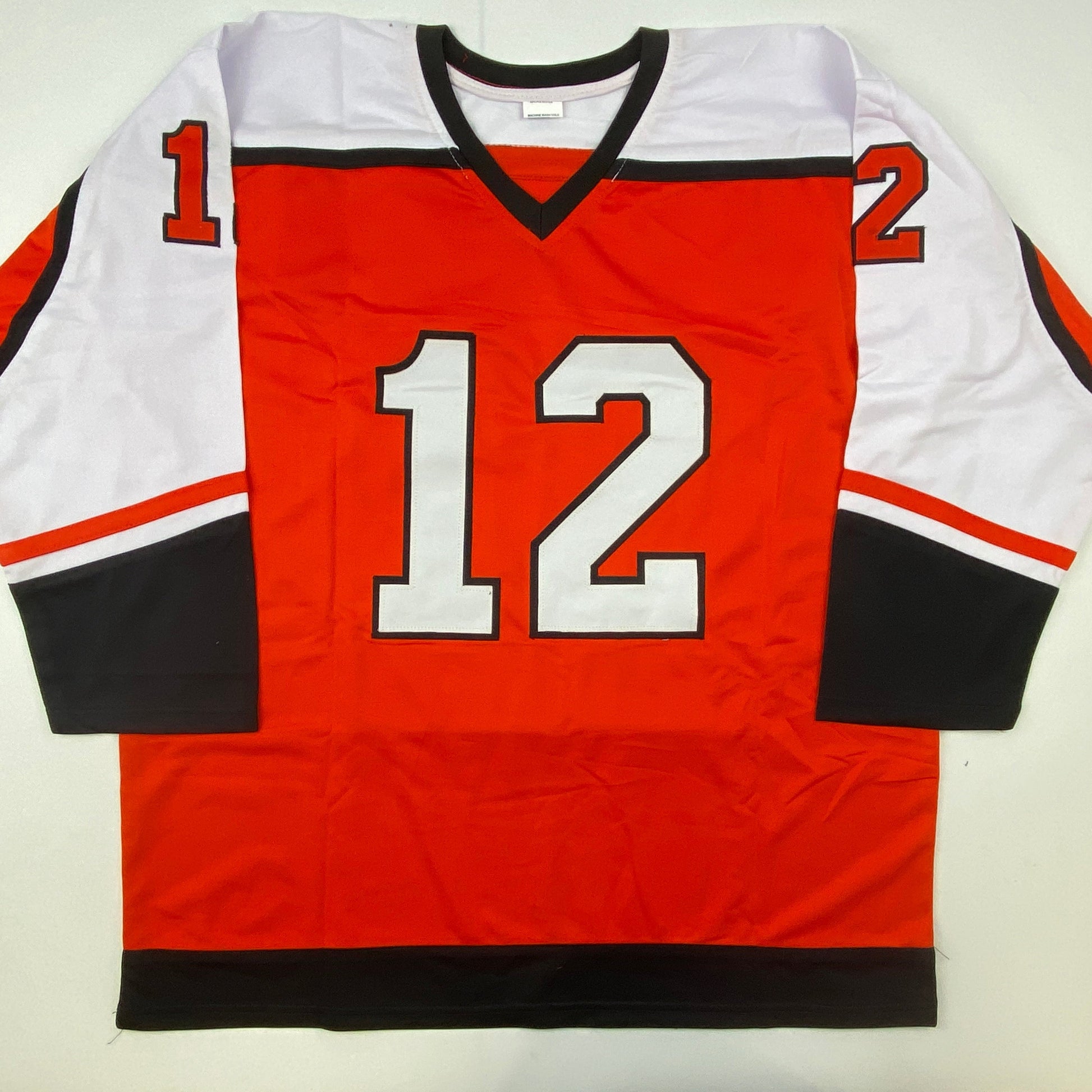 Red, white, and black hockey jersey with number 12 displayed flat against white background, front view.
