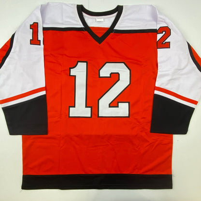 Red, white, and black hockey jersey with number 12 displayed flat against white background, front view.