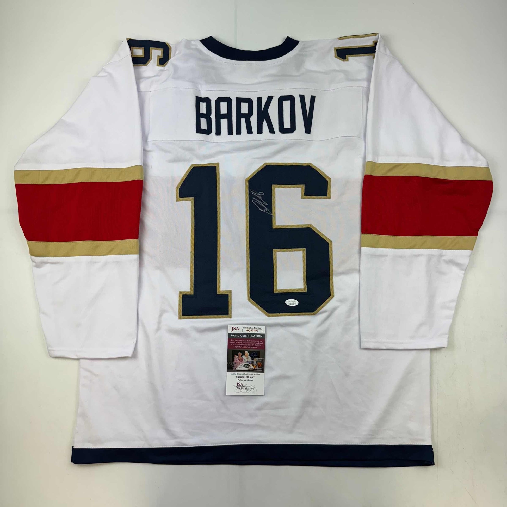 White hockey jersey with red and gold stripes displaying "BARKOV" and number 16, with JSA authentication certificate attached.