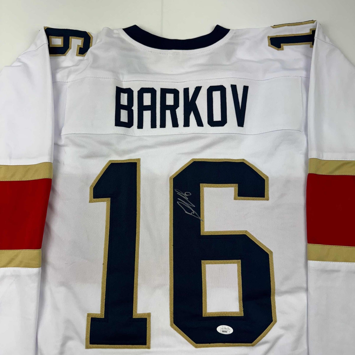 White hockey jersey displaying "BARKOV" and number "16" in navy and gold, with visible autograph on the number.