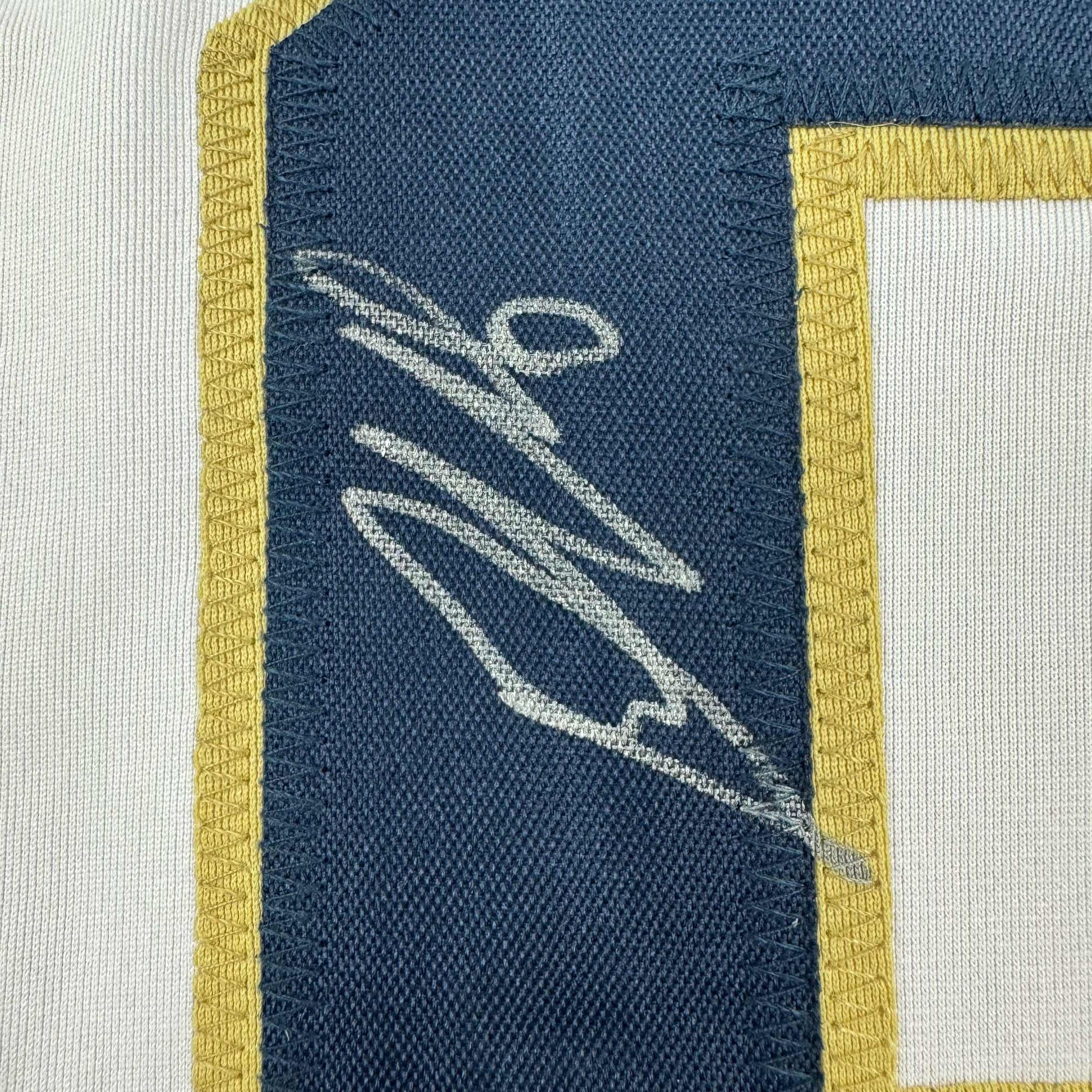 Close-up of navy blue jersey patch with white embroidered stick figure and yellow trim borders.