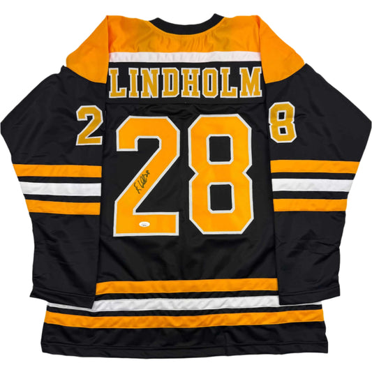 Back view of black and gold Lindholm #28 hockey jersey with orange shoulders, white stripes, and autographed number.