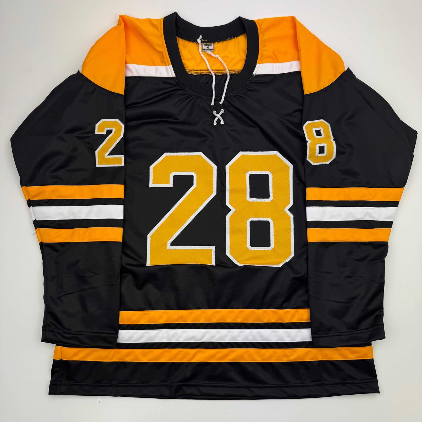 Black and gold hockey jersey with number 28 displayed flat against white background, showing orange and white striped shoulders and sleeves.