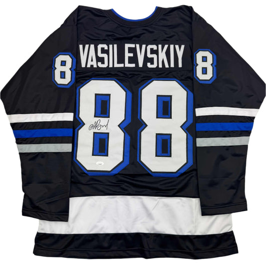 Back view of black hockey jersey with blue and white stripes, number 88, and "VASILEVSKIY" nameplate with autographed signature.