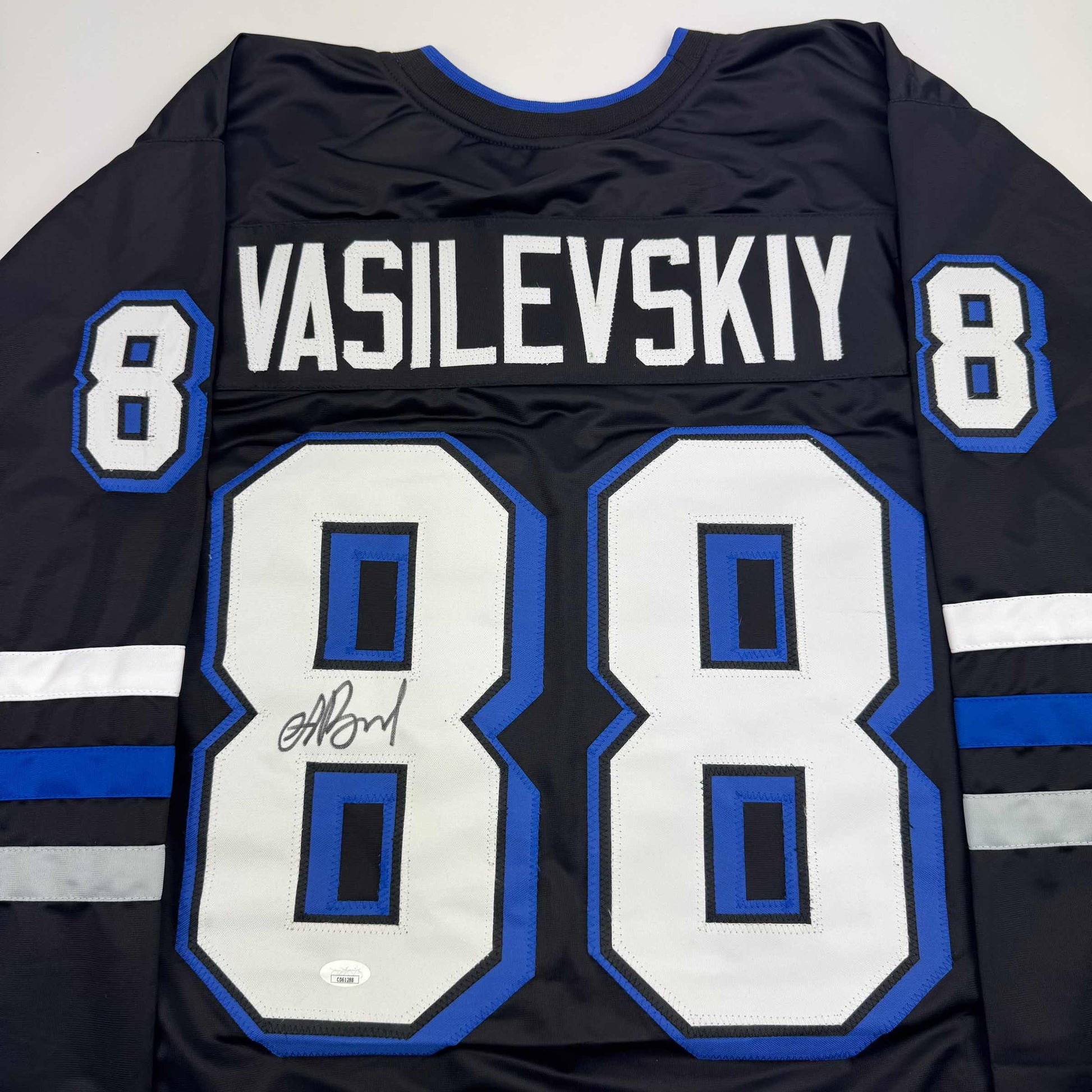 Back view of black hockey jersey with white "VASILEVSKIY" nameplate, number 8, blue and white striping, and autographed number 80 patch.