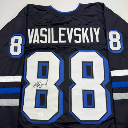Back view of black hockey jersey with white "VASILEVSKIY" nameplate, number 8, blue and white striping, and autographed number 80 patch.