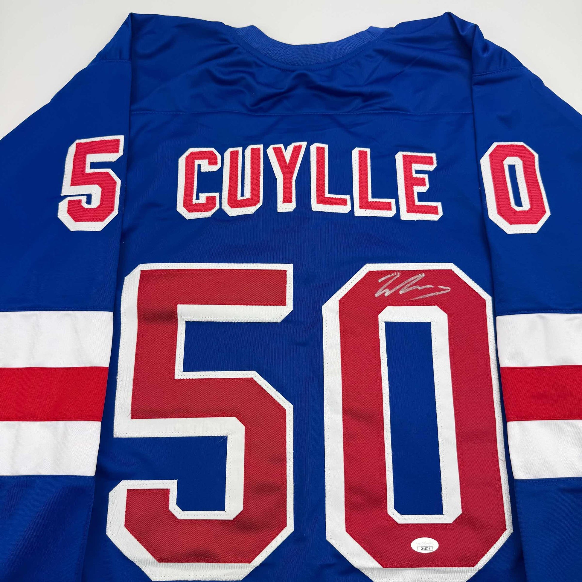 Blue hockey jersey with red and white striped sleeves displaying "CUYLLE" and number 50, with visible autograph on the red numeral.