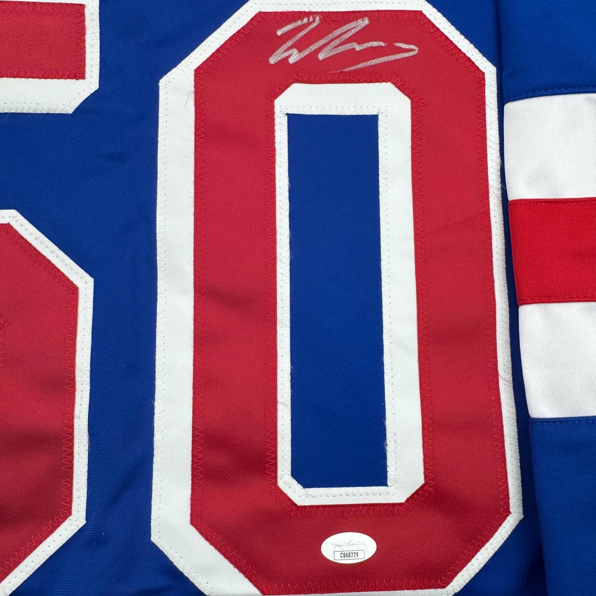Close-up of red number zero on blue hockey jersey with white trim and autograph above numeral.