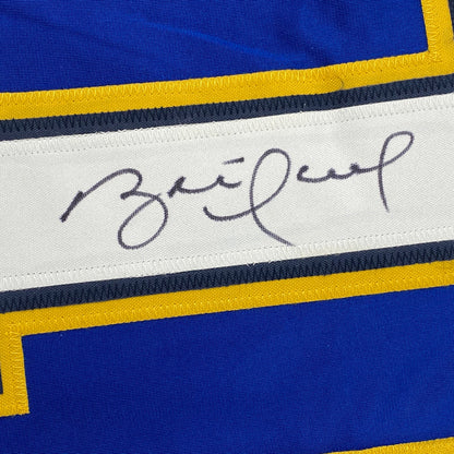 Close-up of handwritten signature on white stripe of blue and yellow striped hockey jersey.