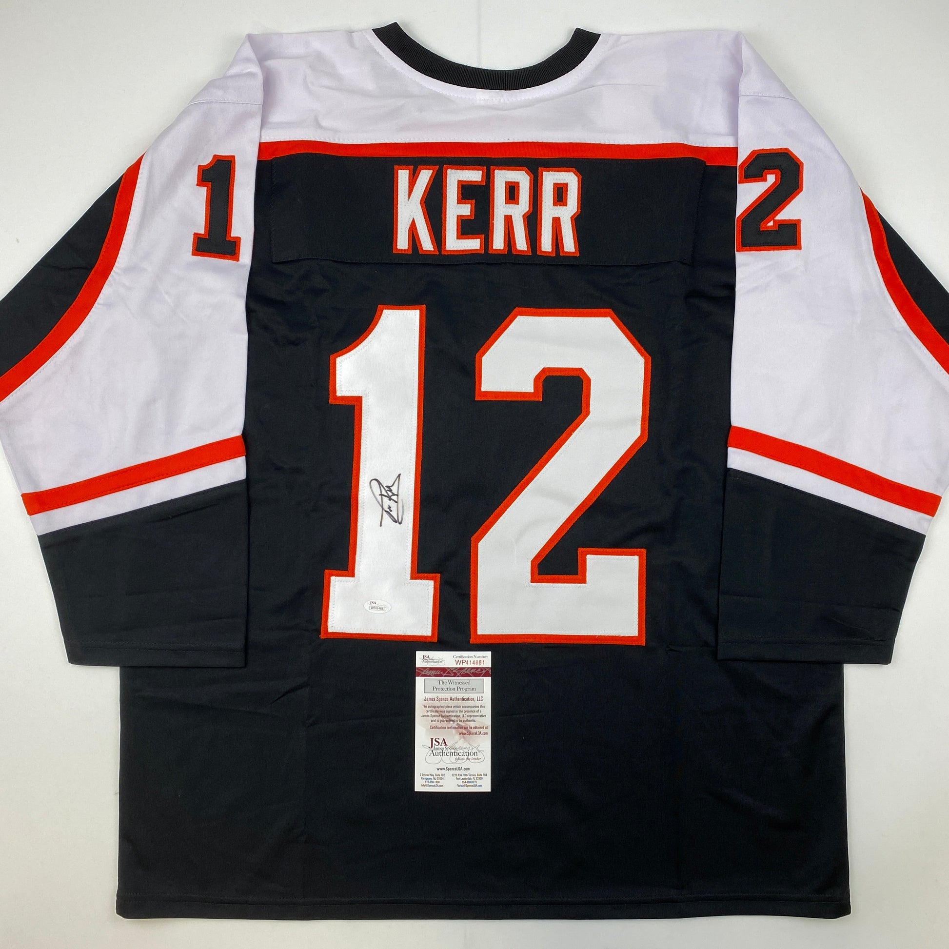Back view of black Philadelphia Flyers hockey jersey number 12 with "KERR" nameplate and autograph, white and red trim, JSA authentication certificate visible.