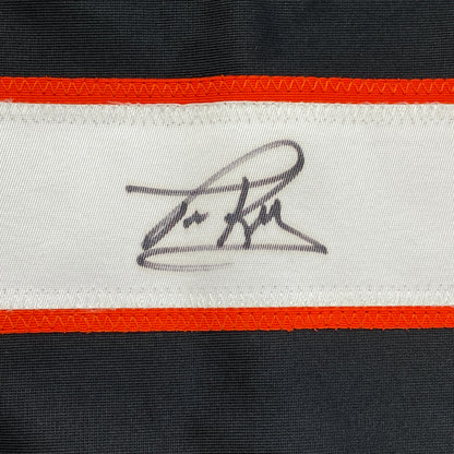 Close-up of handwritten signature on white stripe of black and orange striped hockey jersey.