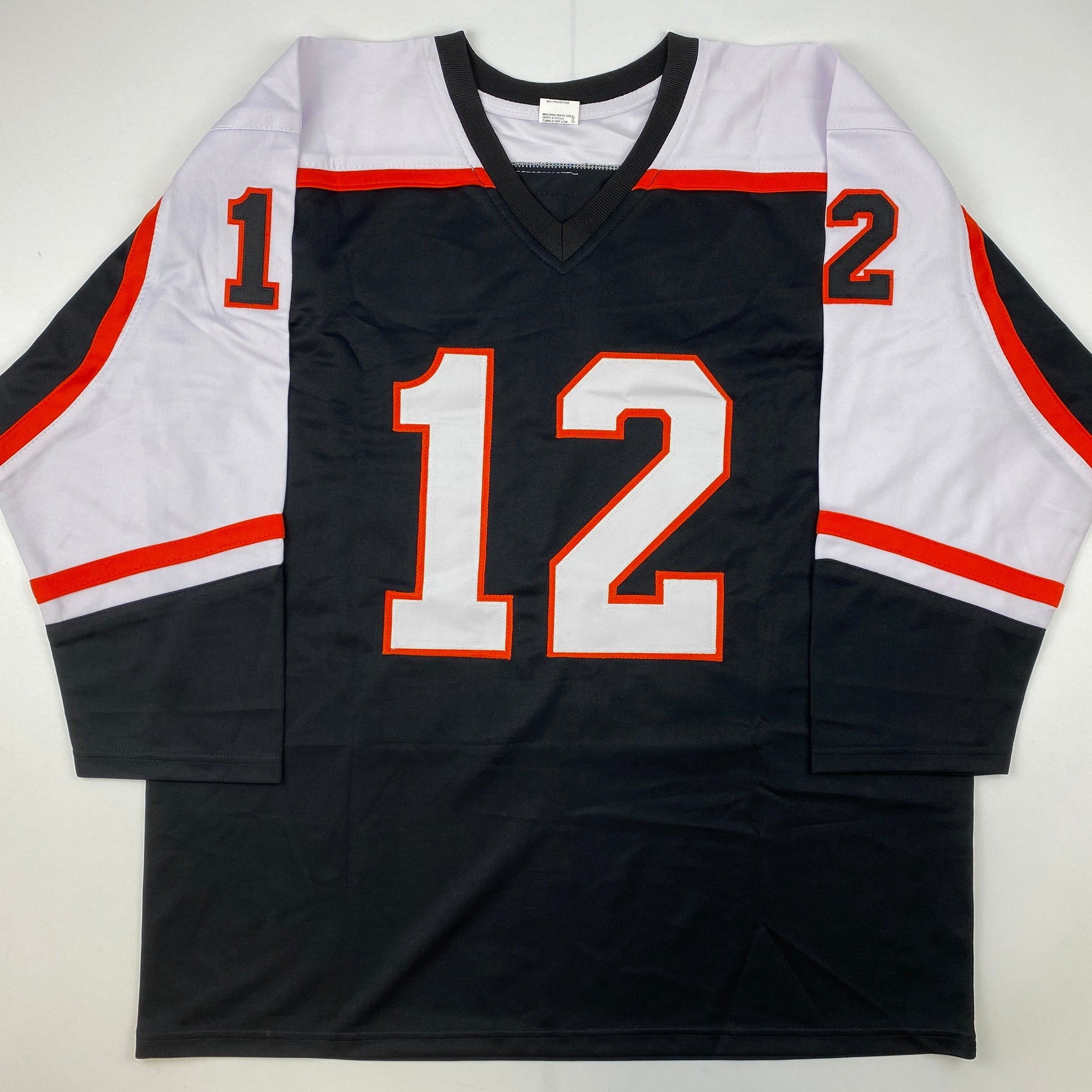 Black hockey jersey with red and white trim displaying number 12 in red and white on front, laid flat against white background.