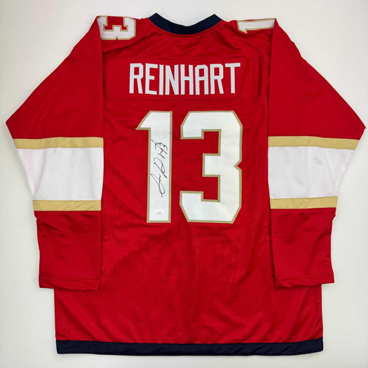 Back view of red Florida hockey jersey number 13 with "REINHART" nameplate and autographed signature on white number.