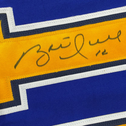Close-up of handwritten signature on yellow stripe of blue and gold hockey jersey with white and black trim.