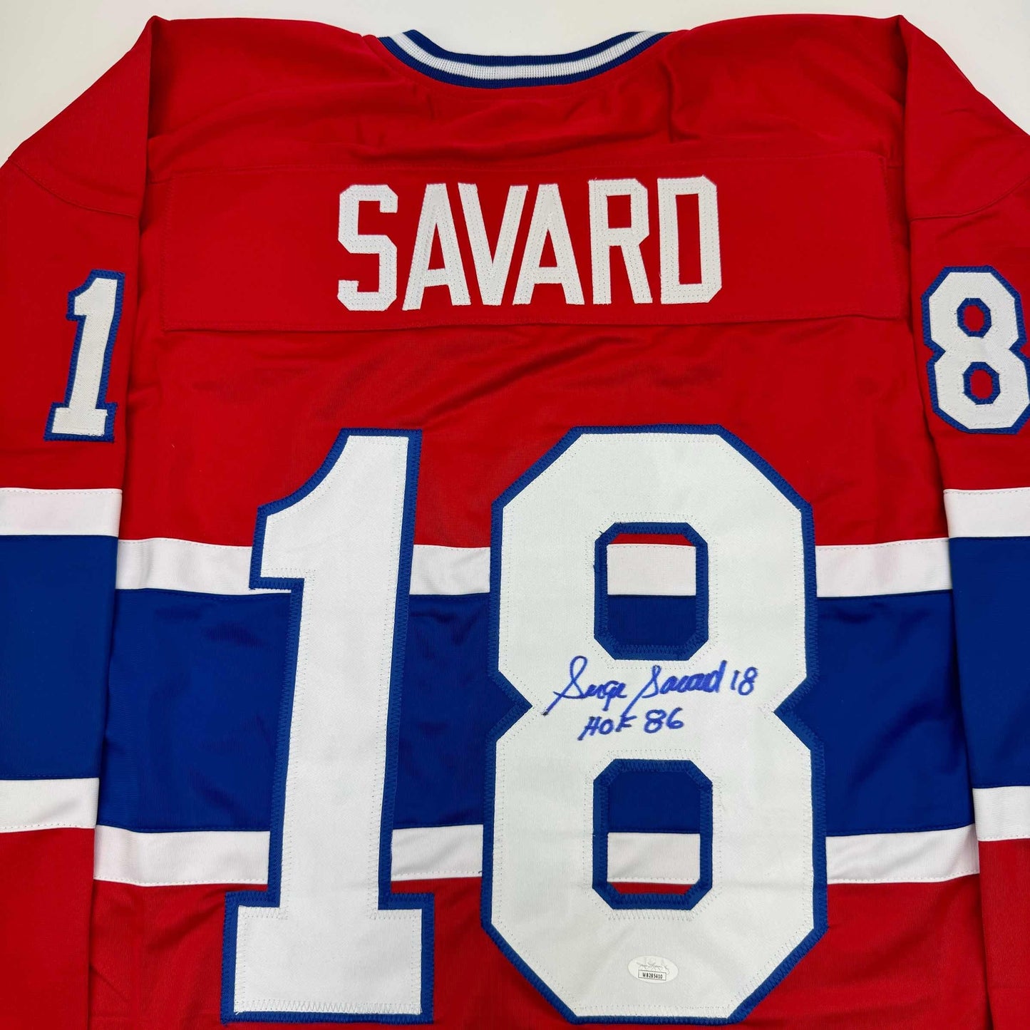 Back view of red, white, and blue Montreal Canadiens hockey jersey with "SAVARD" and number 18 visible, displaying autographed number 18 with "Serge Savard 18 HOF 86" inscription.