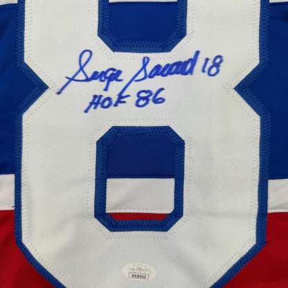 Close-up of blue number 8 on white jersey chest with blue pen autograph reading "Serge Savard 18 HOF 86" and JSA authentication label.