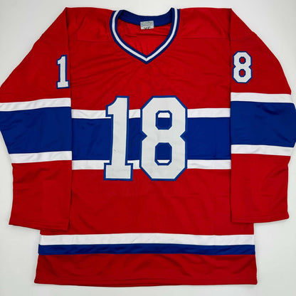 Red and blue Montreal Canadiens hockey jersey number 18 displayed flat against white background, showing front view with white striping and v-neckline.
